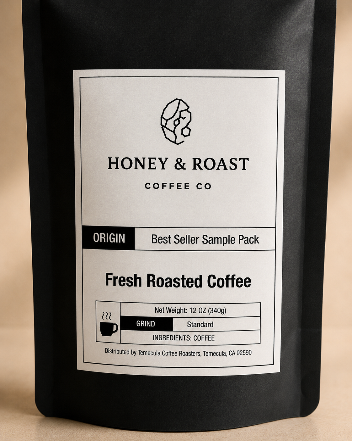 A black stand-up coffee bag with a large white label reading Honey & Roast Coffee Co. Fresh Roasted Coffee, shown against a warm beige background.