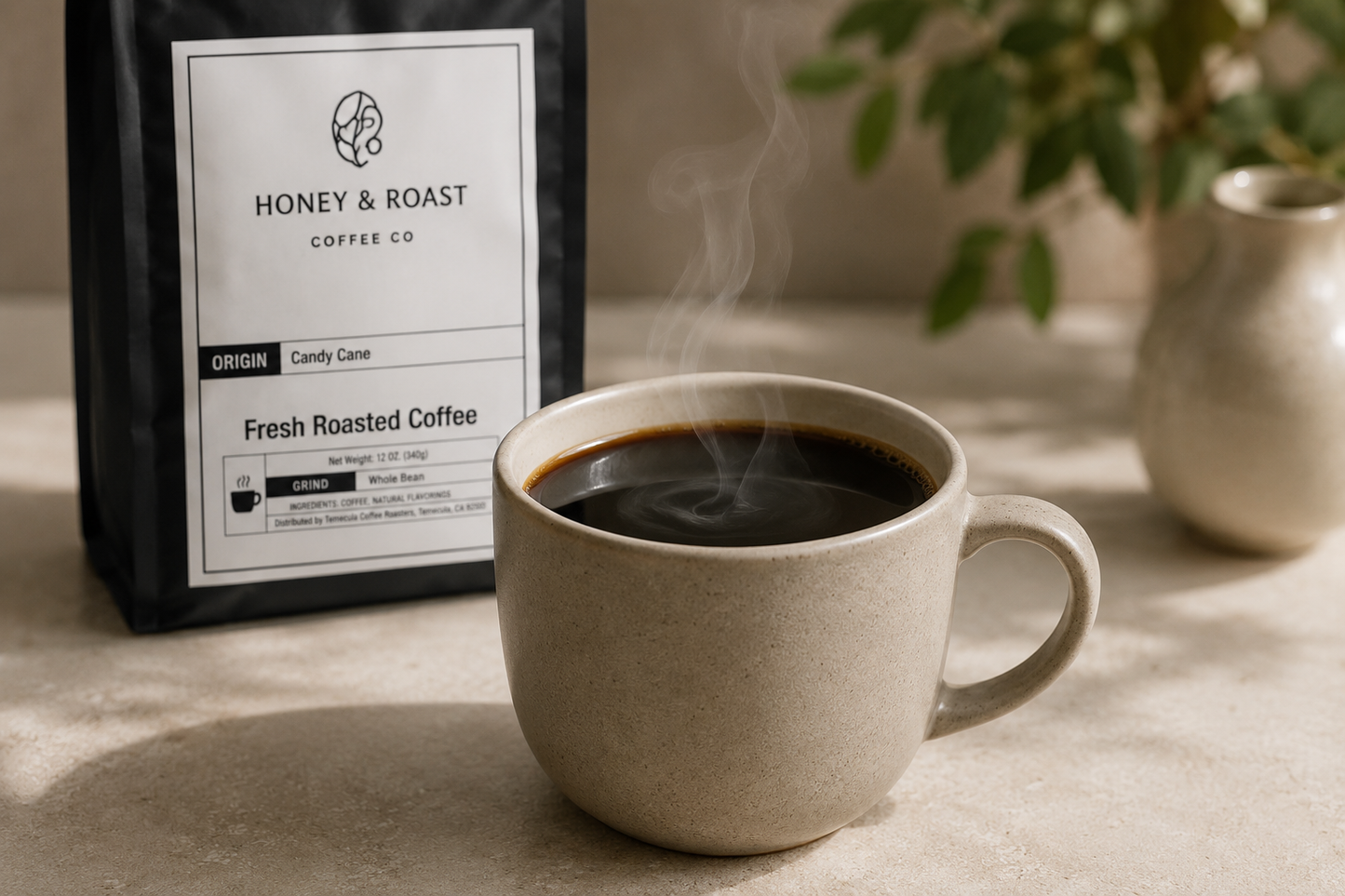 A ceramic coffee mug filled with hot black coffee sits on a tabletop, with steam rising. Behind it is a black bag of Honey & Roast Coffee Co.