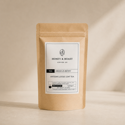 A kraft paper stand-up pouch of Honey & Roast Coffee Co. Artisan Loose Leaf Tea, Hibiscus Berry, standing on a beige surface with soft shadows.
