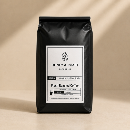 A black bag of Honey & Roast Coffee Co. Fresh Roasted Coffee, Mexico Coffee Pods, standing upright on a beige surface with soft diagonal shadows.