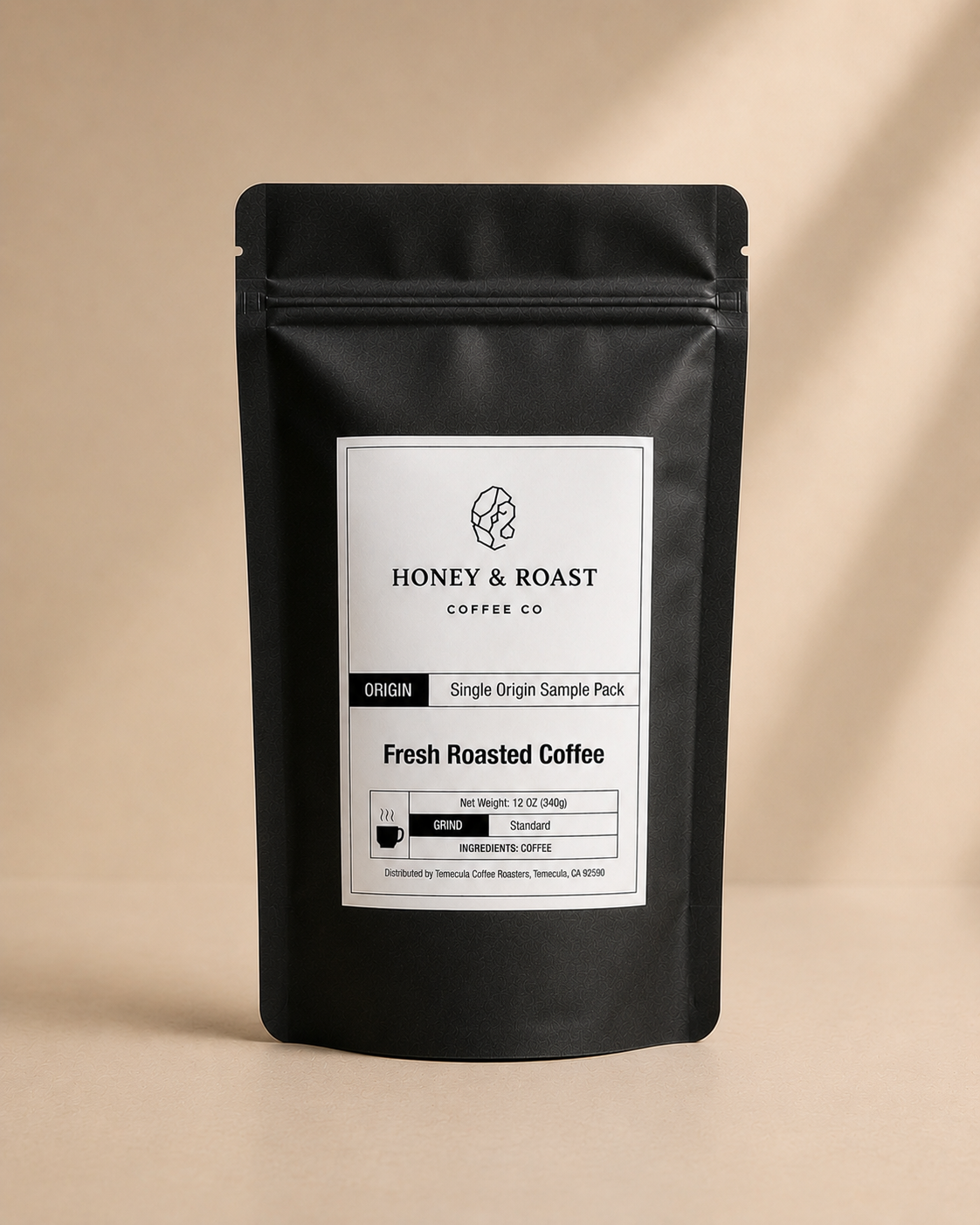 A black stand-up pouch of Honey & Roast Coffee Co. Fresh Roasted Coffee, Single Origin Sample Pack, set against a warm beige background with soft diagonal shadows.