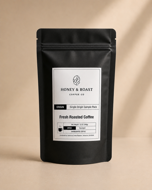 A black stand-up pouch of Honey & Roast Coffee Co. Fresh Roasted Coffee, Single Origin Sample Pack, set against a warm beige background with soft diagonal shadows.