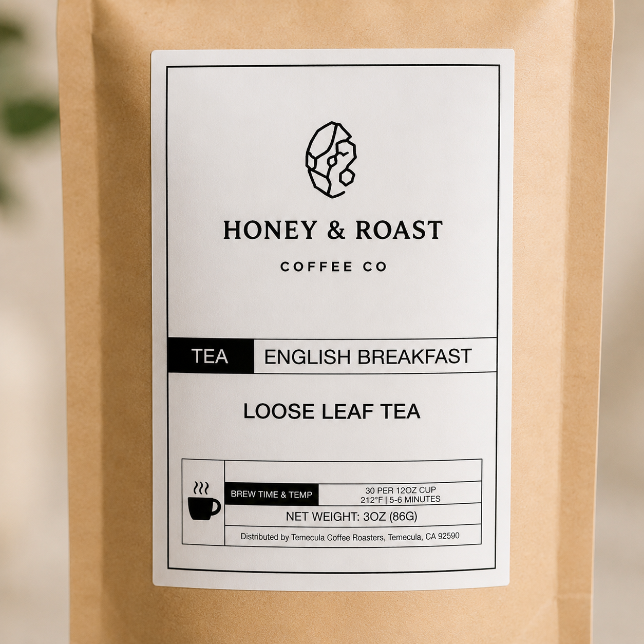 A close-up of a kraft paper coffee bag with a large white label reading Honey & Roast Coffee Co. Tea English Breakfast Loose Leaf Tea.