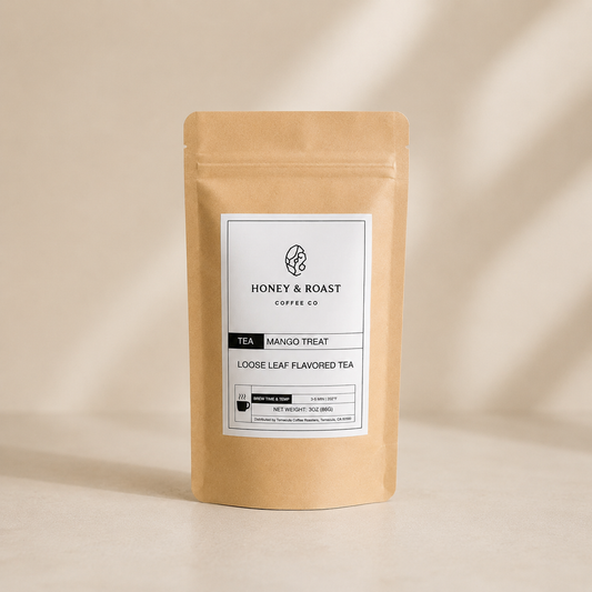 A kraft paper stand-up pouch of Honey & Roast Coffee Co. Loose Leaf Flavored Tea, Mango Treat, standing on a light beige surface with soft diagonal shadows.