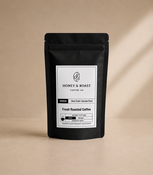 A black stand-up coffee bag with a white front label reading Honey & Roast Coffee Co, photographed on a warm beige background with soft diagonal shadows.